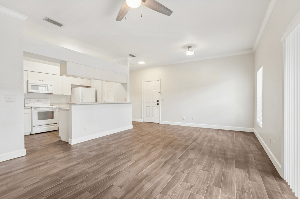 A spacious kitchen with white cabinets and a wooden floor.